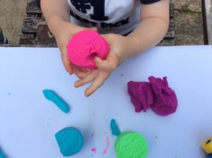 Toddler playing with bright and colorful putty or clay play doh